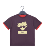 A dark purple ringer t-shirt with red trim on the sleeves and collar, featuring a cream-colored graffiti-style graphic that reads 'JONESYa+' above the number '88' on a cream block.